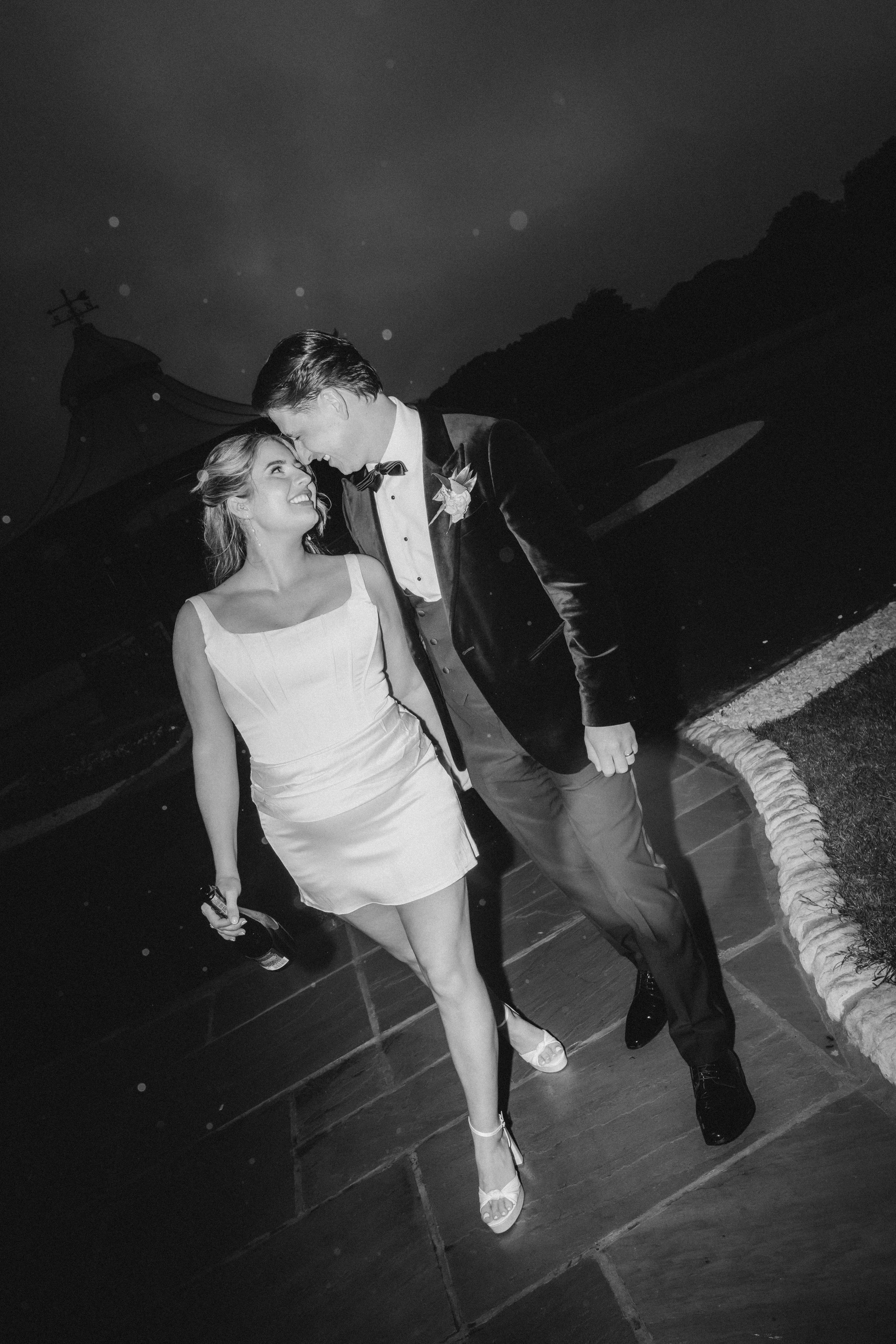 Emma and Frazer laughing together outside at the end of their wedding night.