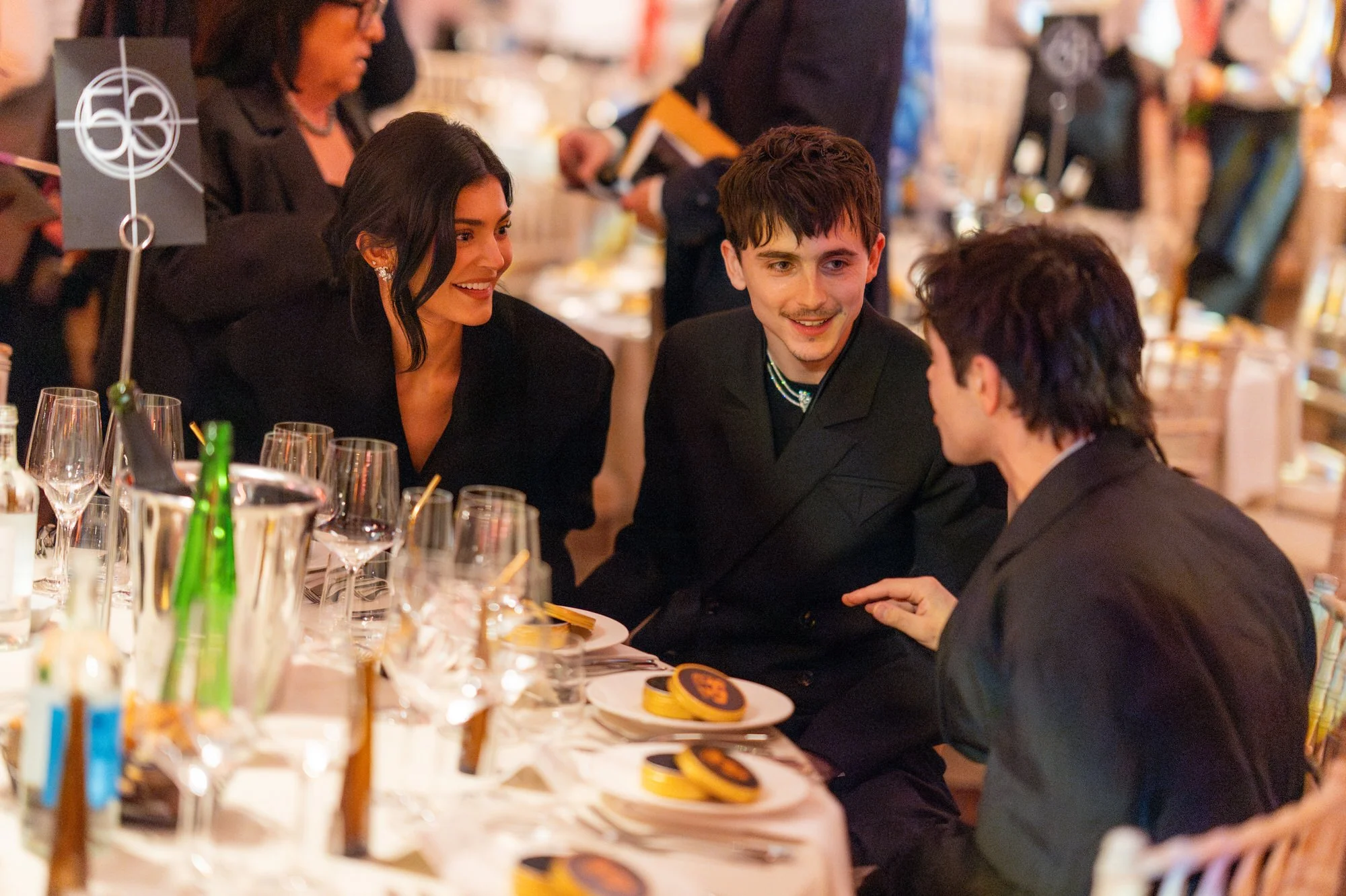 Timothée Chalamet and Kylie Jenner chatting with a guest at the BAFTA dinner.