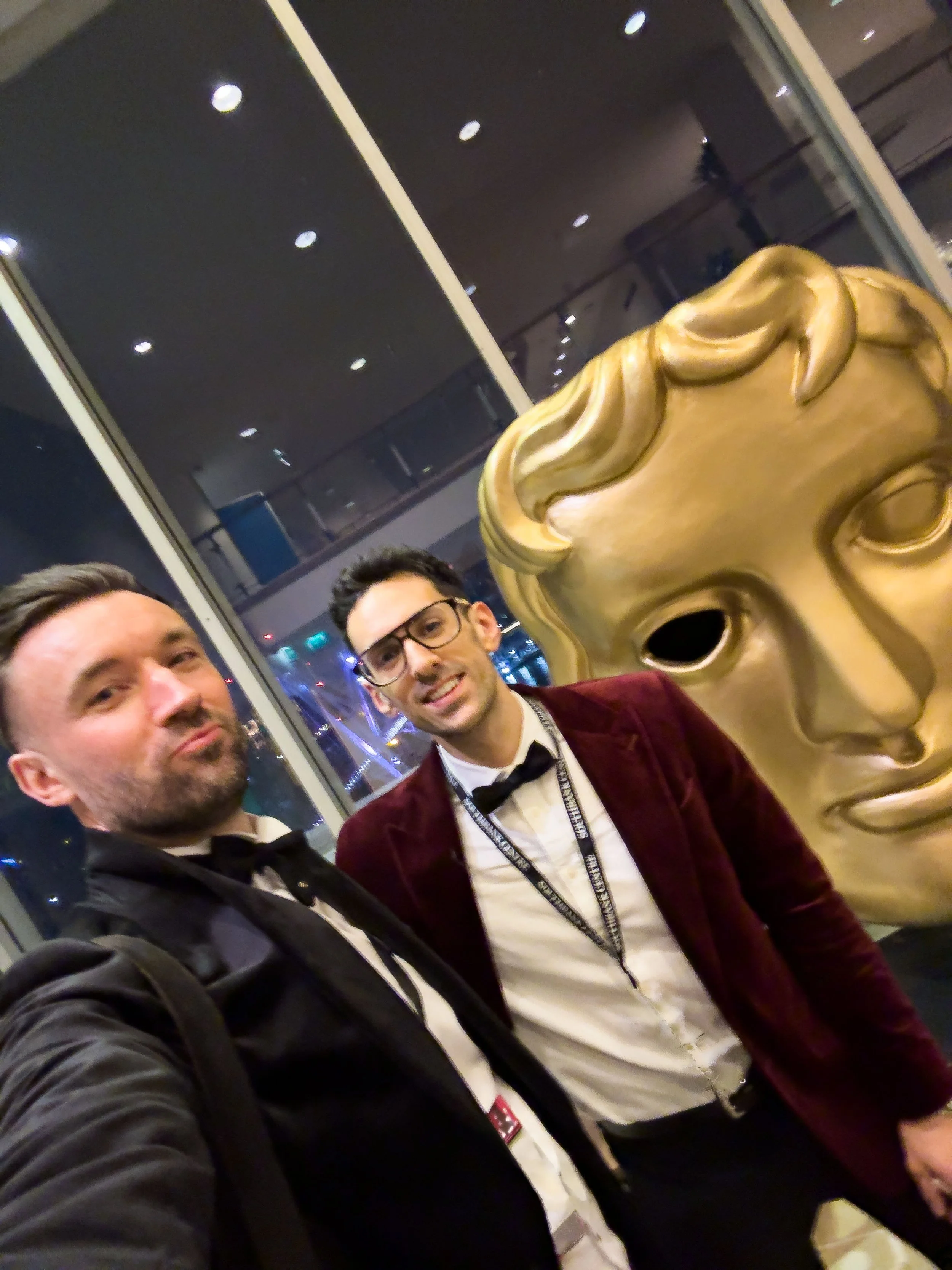 John Clark and Carlo Paloni beside a BAFTA mask.
