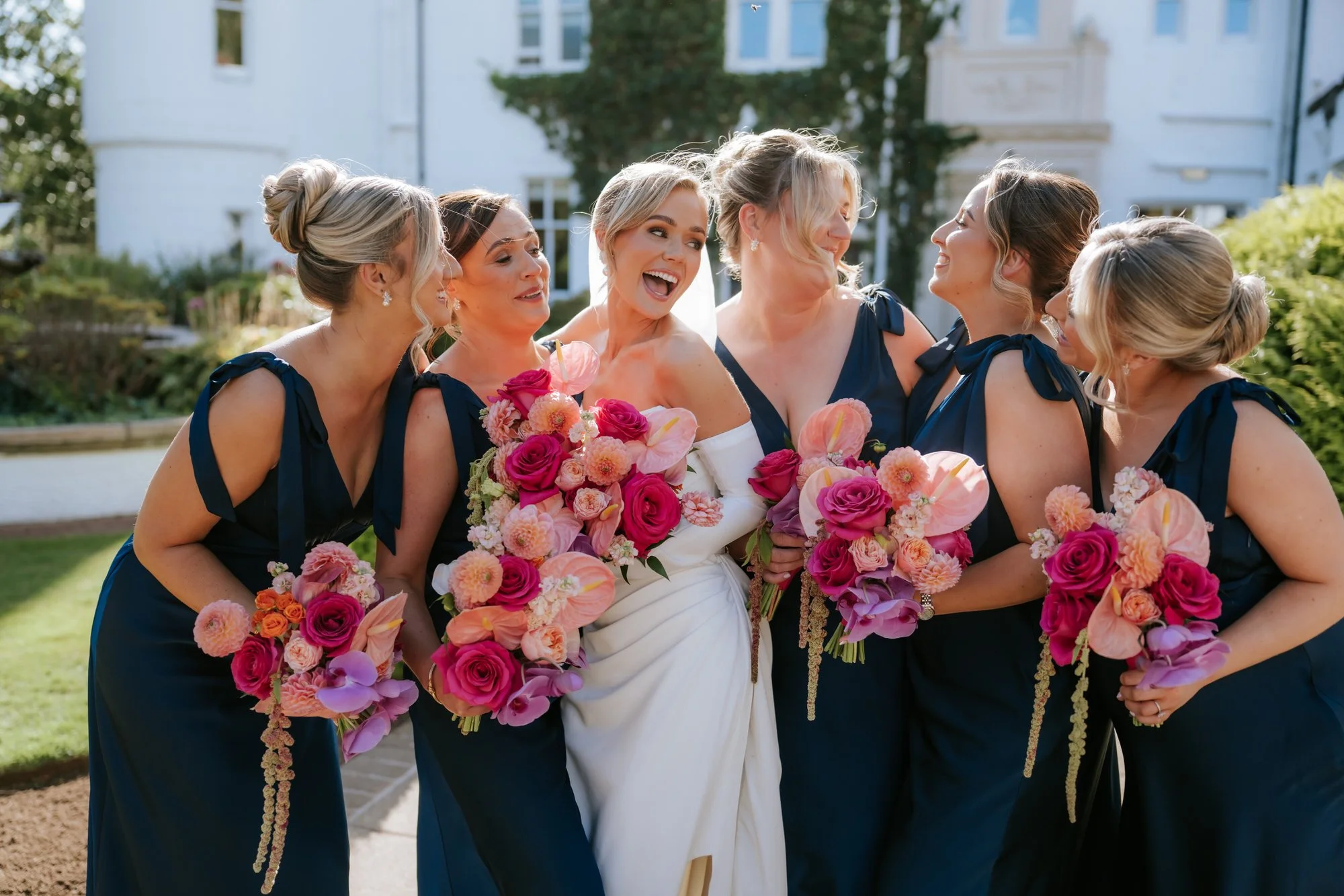 Fiona laughing with her bridesmaids and their colourful bouquets.
