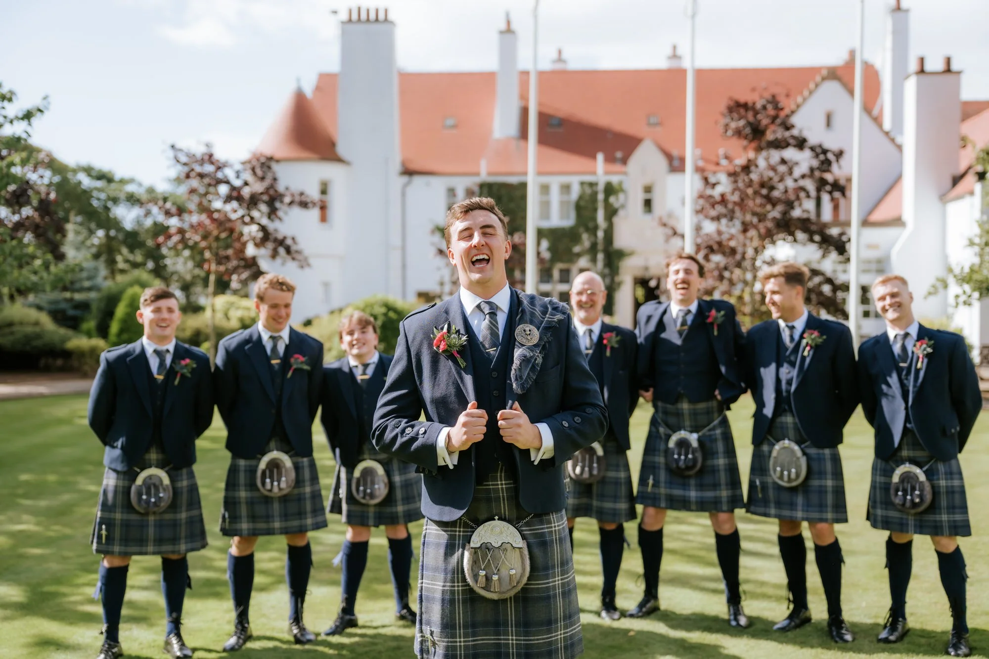 Connor laughing with his groomsmen outside Lochgreen House Hotel.