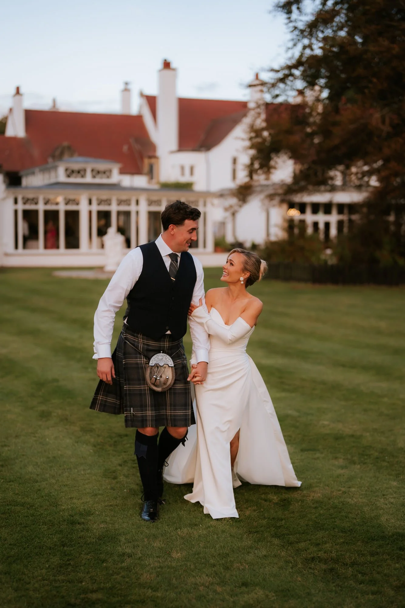 Fiona and Connor walking across the lawn with Lochgreen behind them.