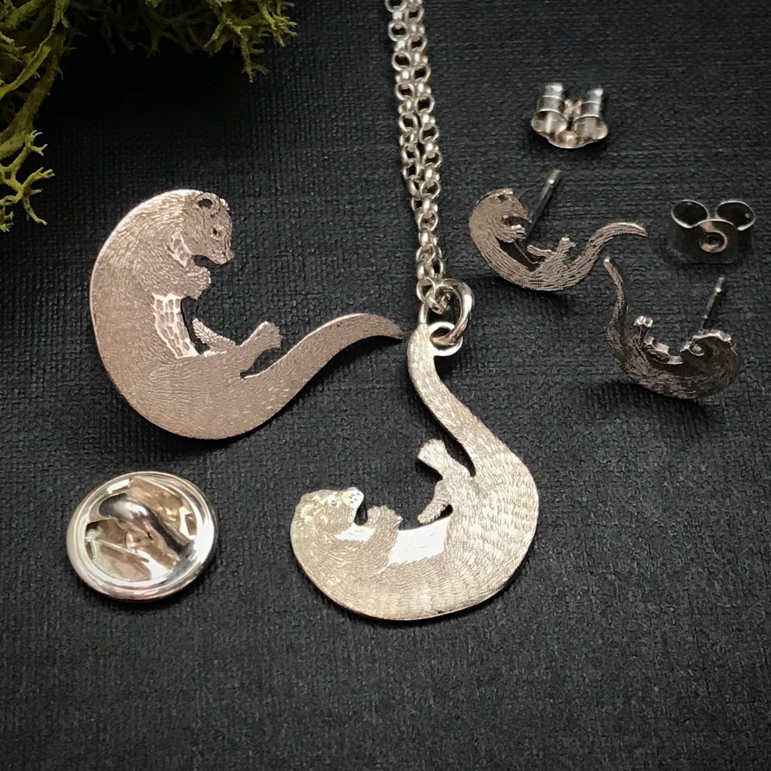 Handmade Playing Otter Jewellery including pendant, earrings and lapel pin.