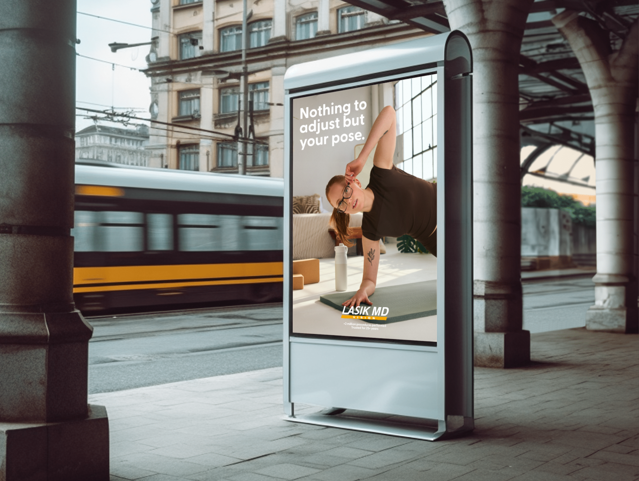 Affiche publicitaire LASIK MD dans un abribus, montrant une femme pratiquant le yoga avec le message « Nothing to adjust but your pose ».