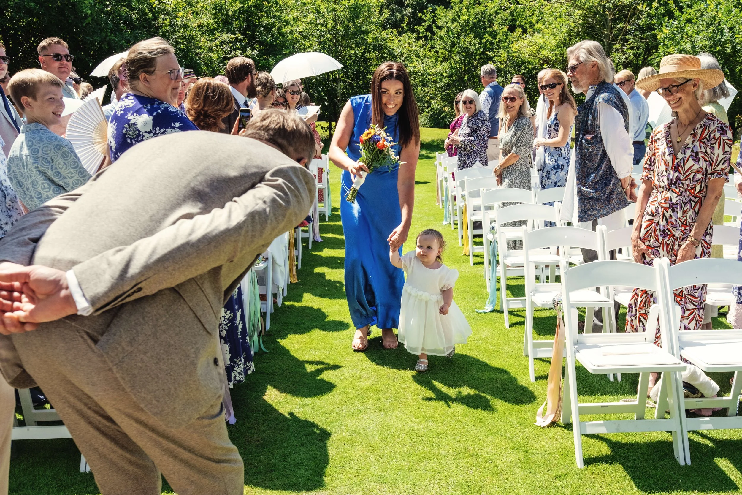 Flower girl escorted by bridesmaid up the aisle