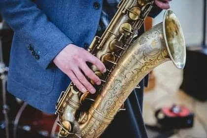 Close-up of a musician in a blue jacket playing a saxophone.
