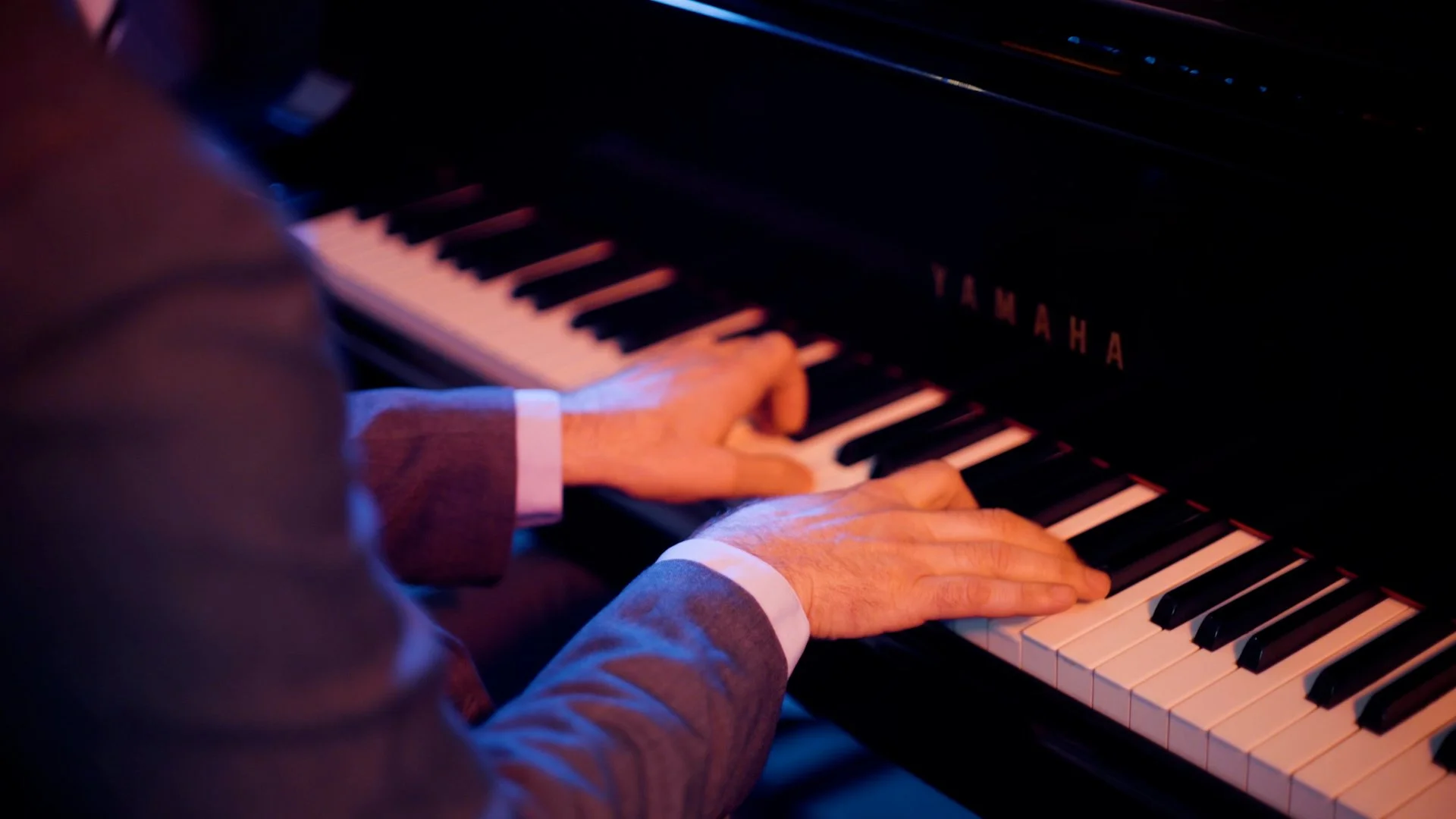 Close-up of a pianist’s hands playing a Yamaha piano.