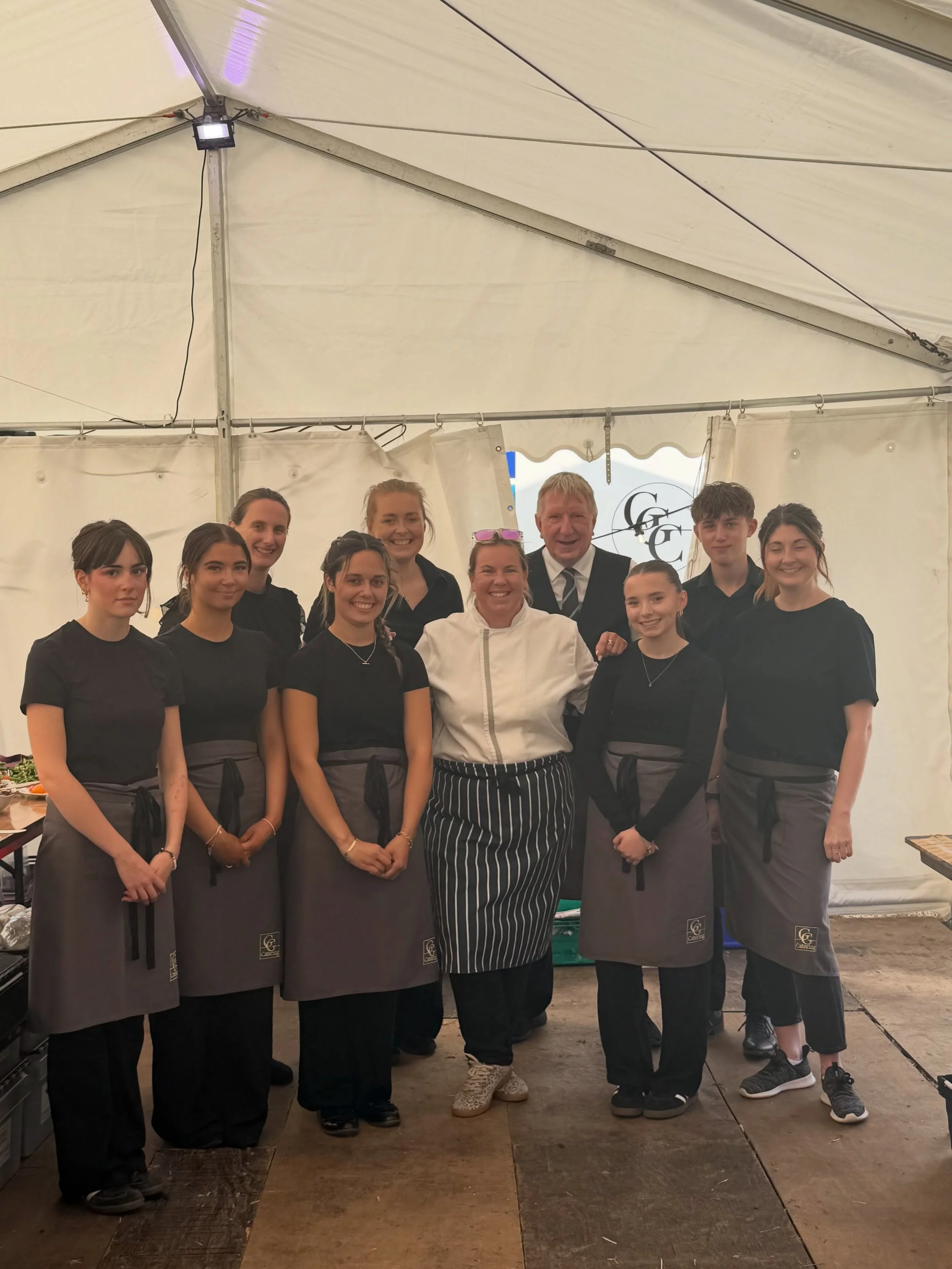 The Get Gourmet Catering team smiling together in a marquee.