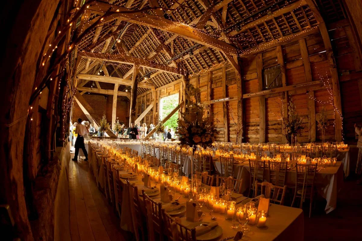Candlelit wedding tables beneath the timber beams at Pimhill Barn.