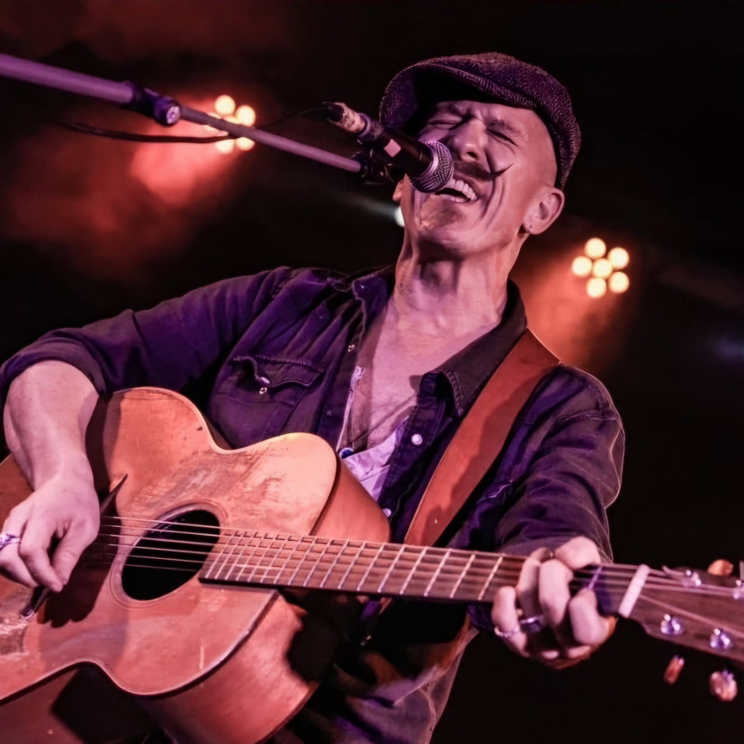 Foy Vance playing a guitar on stage using a handmade Lost Soul Leather guitar strap.