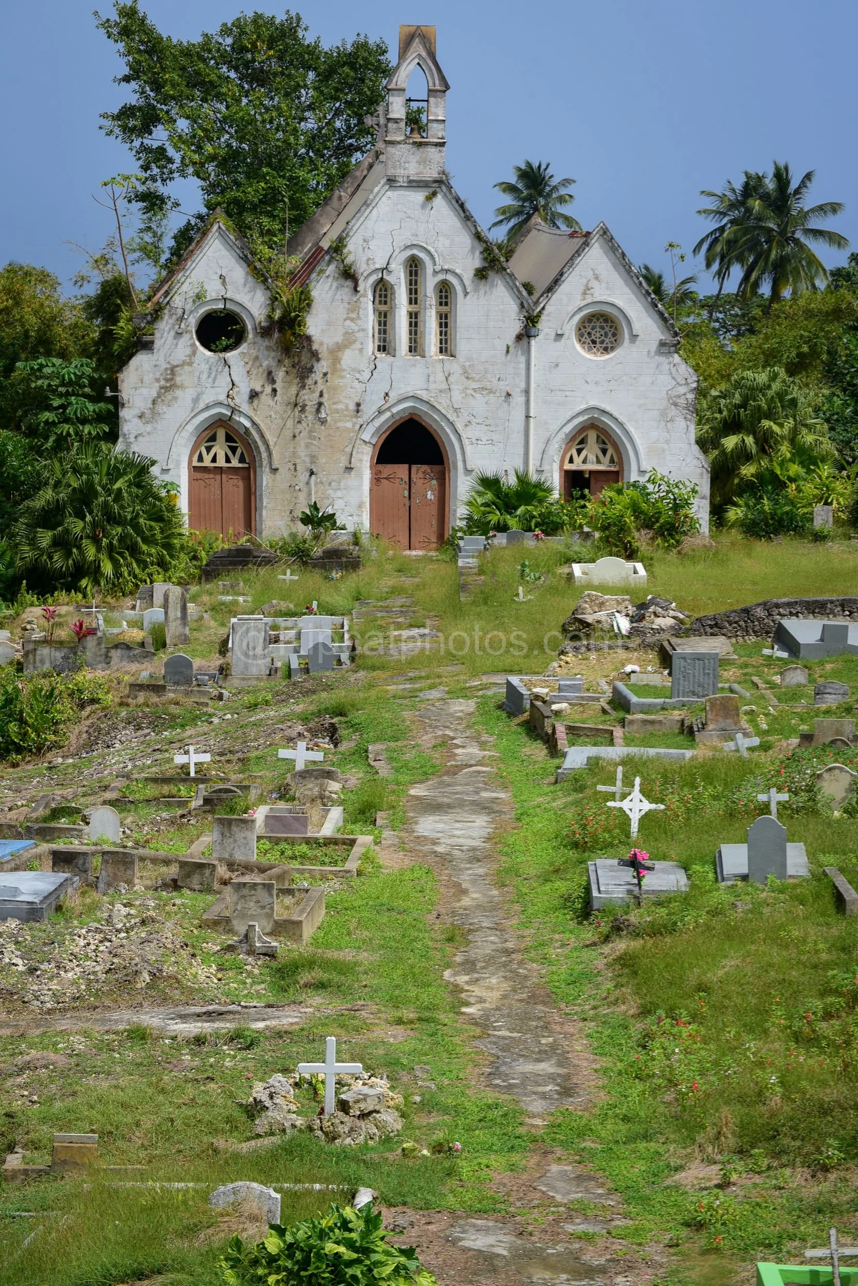 The ruined Gothic facade of St Joseph's Church in Barbados, surrounded by a hillside cemetery. Kipcatphotos.com

St Joseph's Church stands roofless and cracked, its Gothic arched doorways, rose window and bell tower still striking against the sky, ov