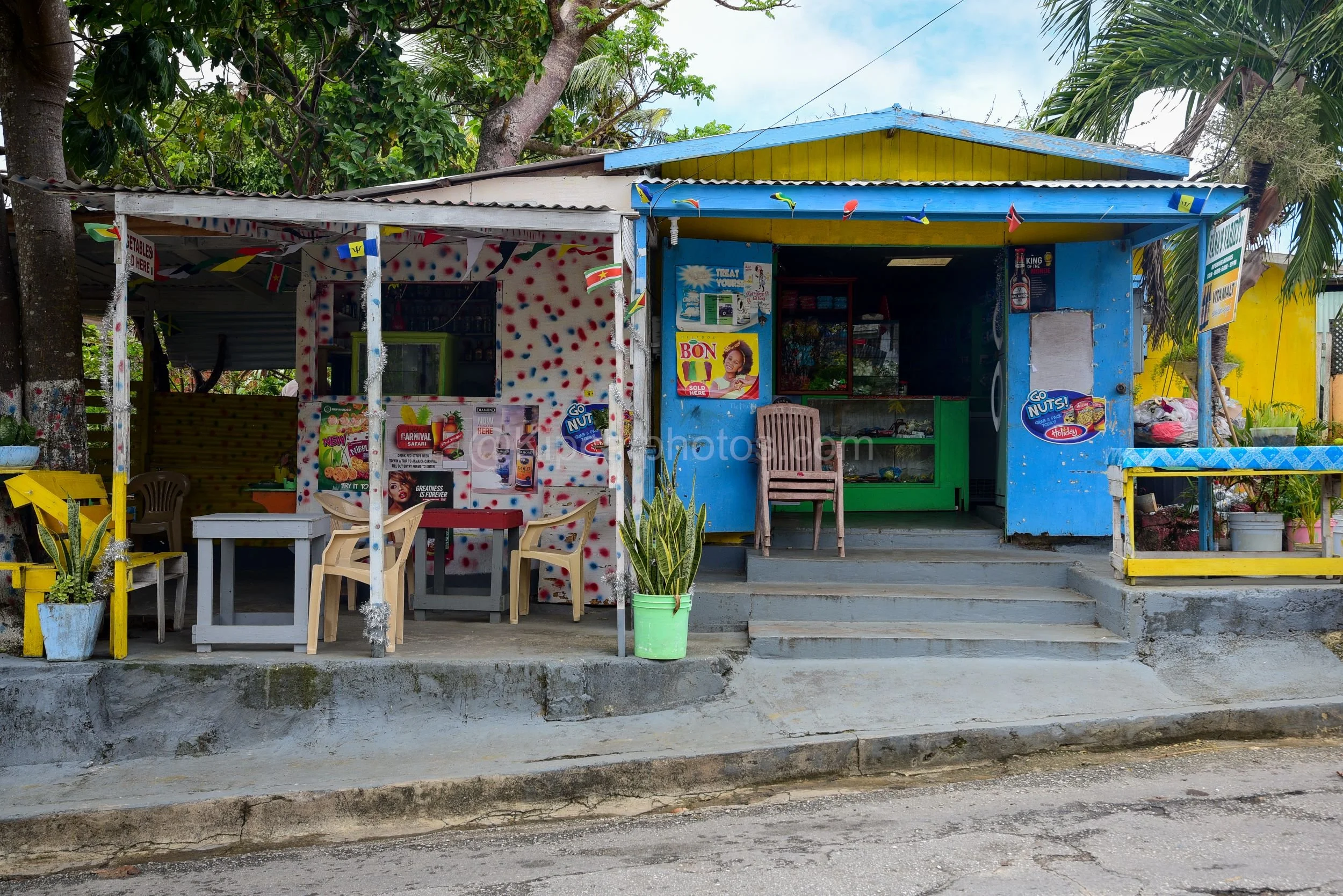 A brightly painted shop, Vana's Variety, in Barbados, decorated with polka dots, flags and advertising posters. Kipcatphotos.com

Splashes of red, white, blue and yellow cover this lively roadside rum shop and snackette, its walls plastered with drin