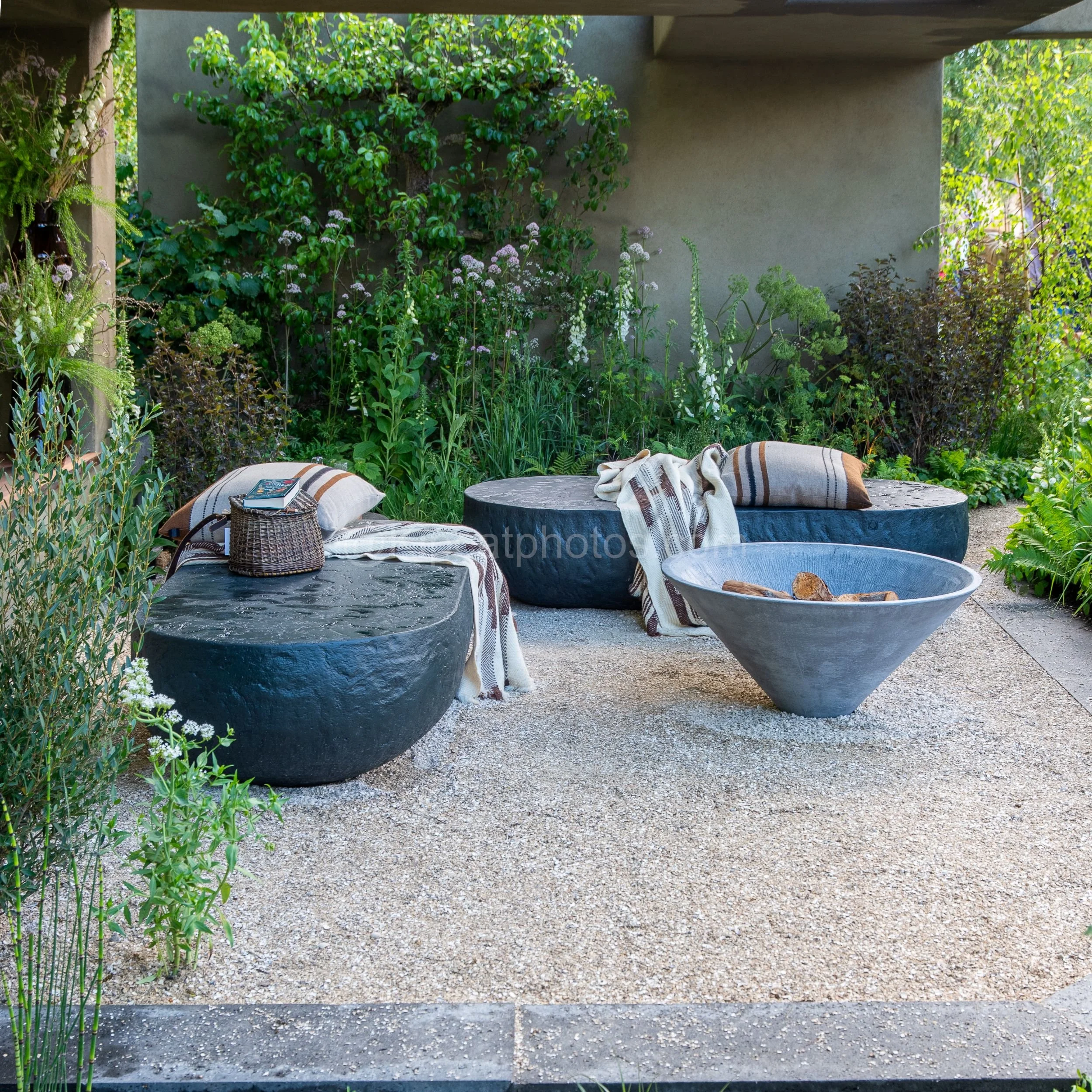 Round stone bowl benches and cushions beneath a concrete pergola in the Baz Grainger garden at RHS Chelsea Flower Show 2026

A relaxed seating area with rounded stone bowl benches, striped cushions and throws beneath a concrete pergola, surrounded by