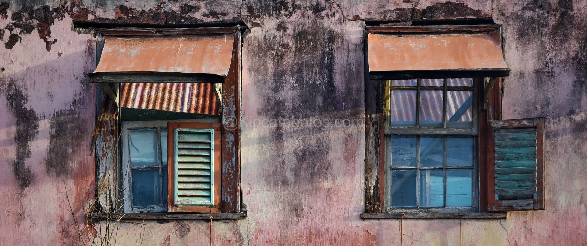 Shuttered jalousi windows on old pink townhouse in Speightstown Barbados.

Close up portrait of shuttered jalousie windows on a crumbling pink house in Speightstown, Barbados.