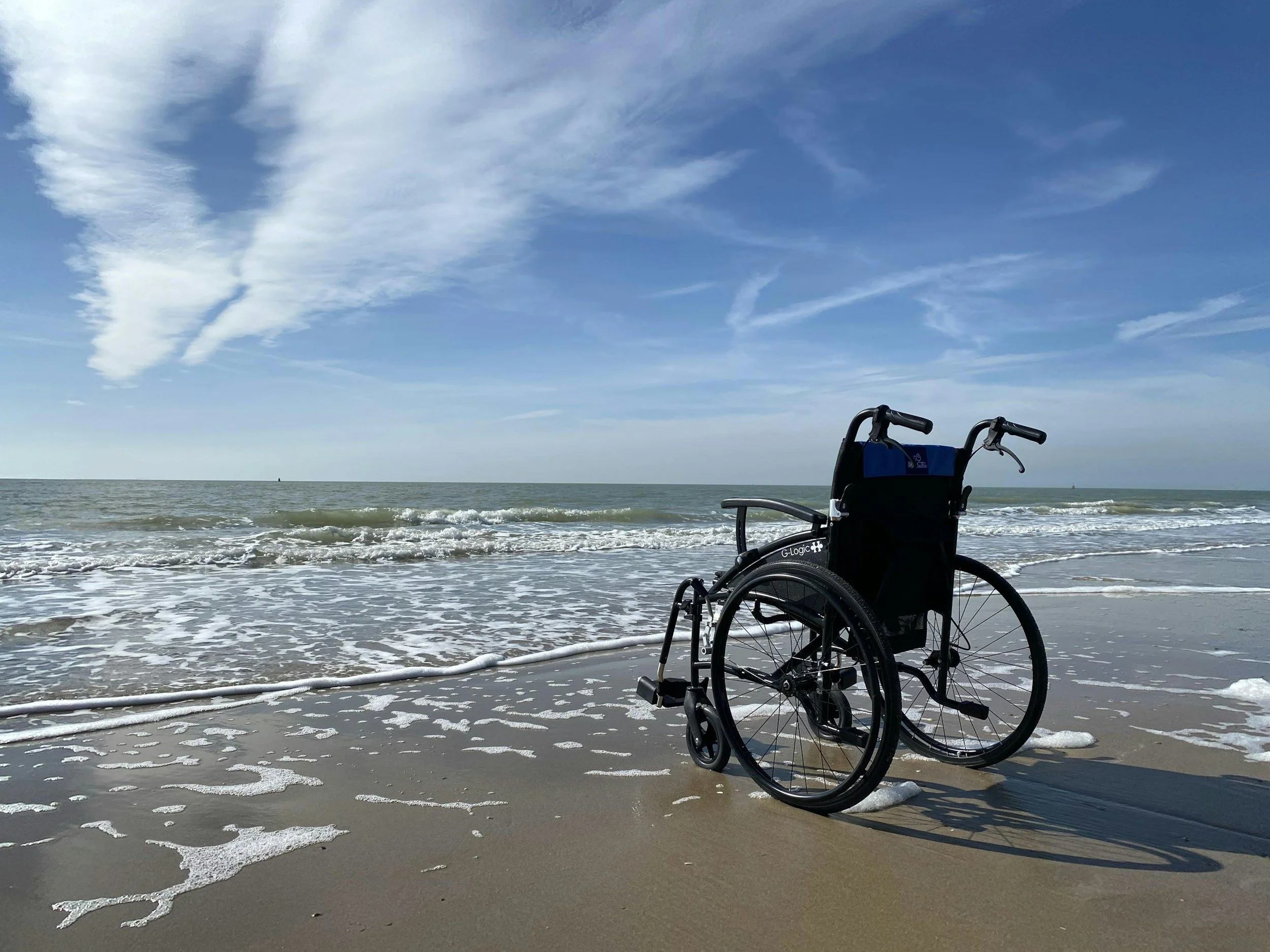unoccupied wheelchair on a beach facing the water
