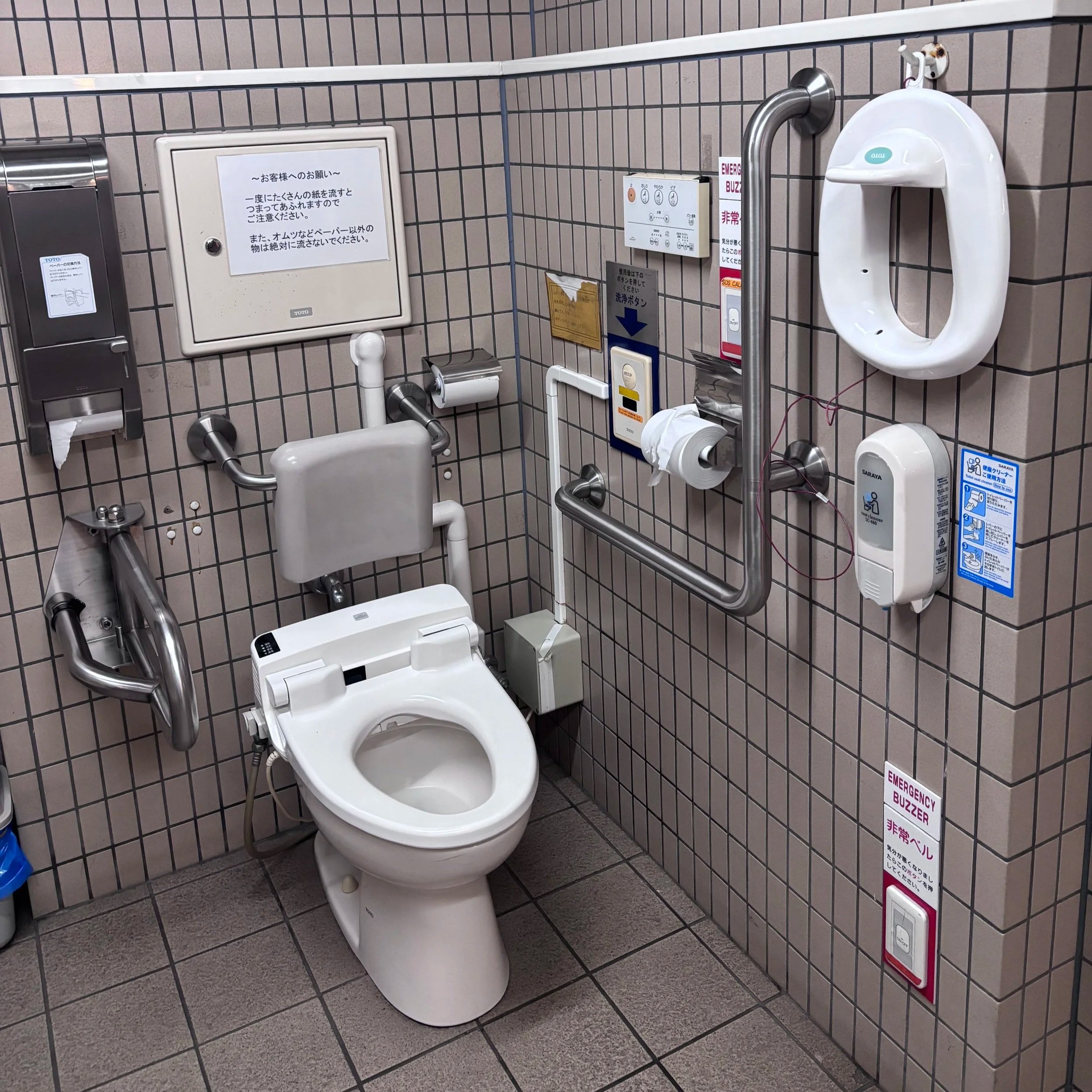 Accessible toilet set up with a back support, multiple bars, call light