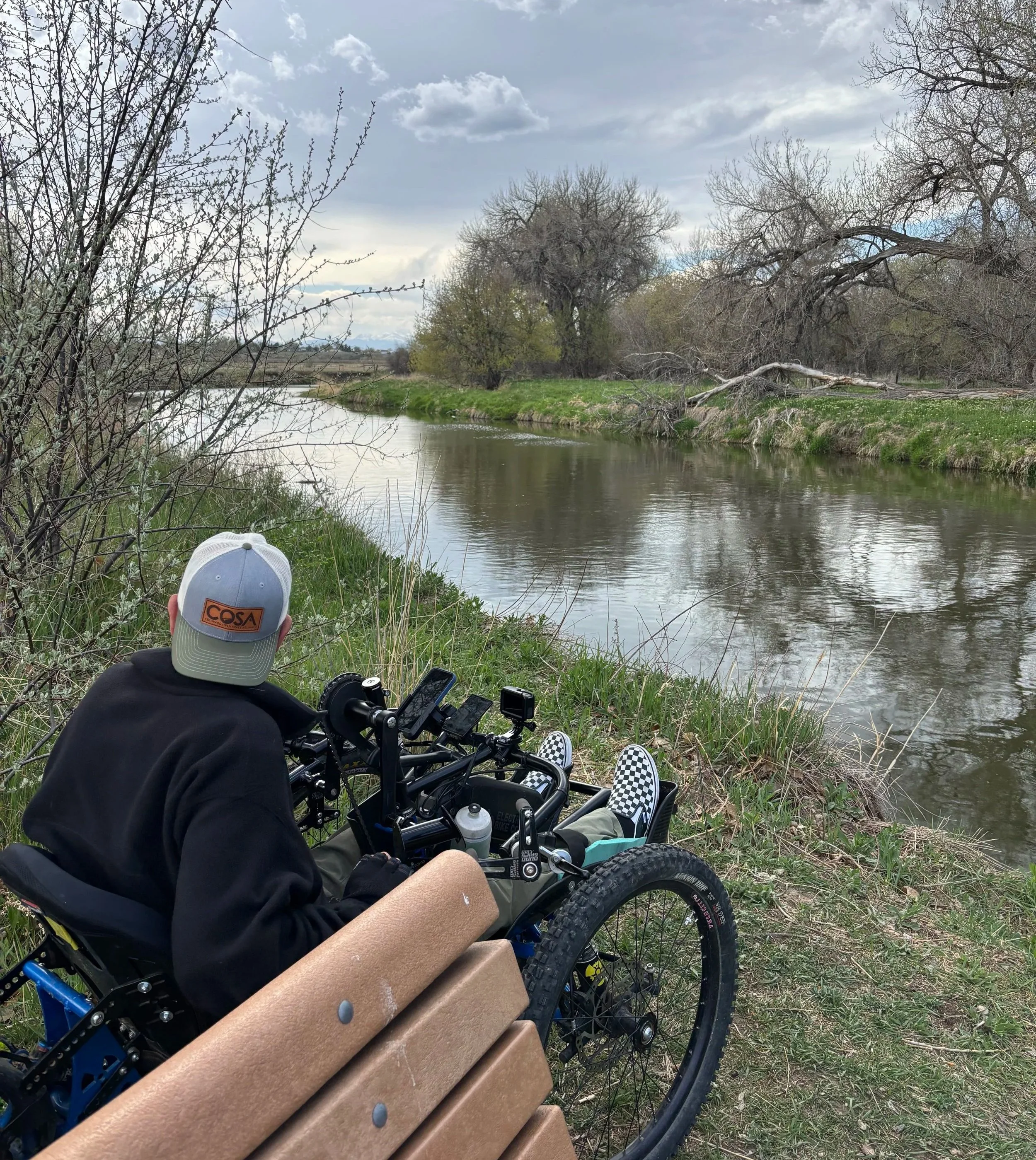 Bench with a flat wheelchair space beside it overlooking the river and wide open skies