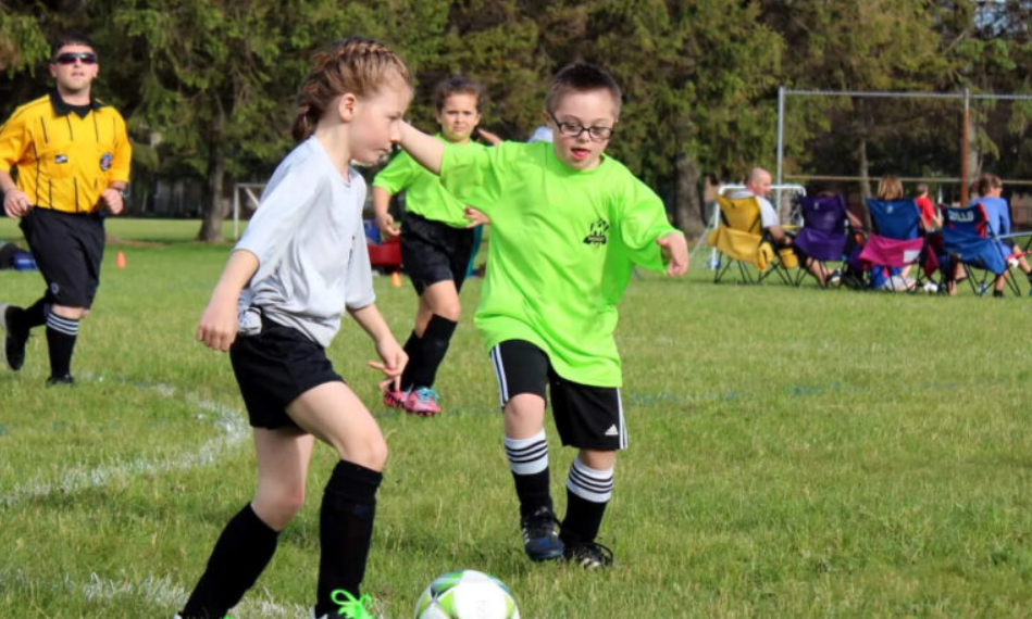 two kids are playing soccer with one dribbling and one running toward her