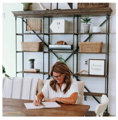 Kim Snodgrass, a professional organizer, at her desk with a choose happy sign