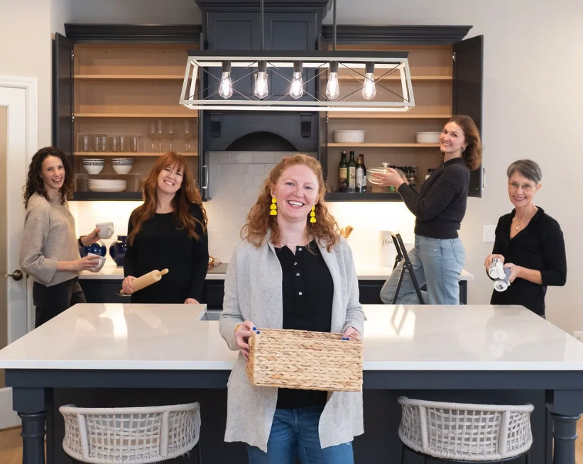 The team at Clear Spaces organizing is working to organize a navy blue kitchen. It features Missi Mills, the owner of Clear Spaces, and four members of her team