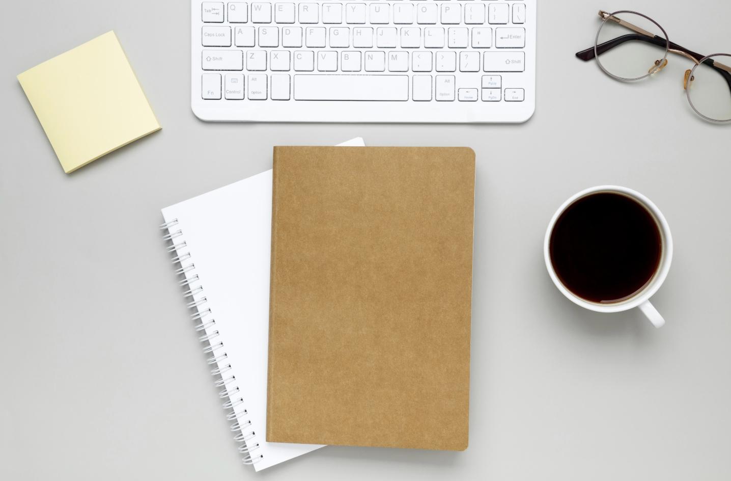 Minimal study desk with laptop showing blank document, notebook, and coffee representing difficulty starting a task.