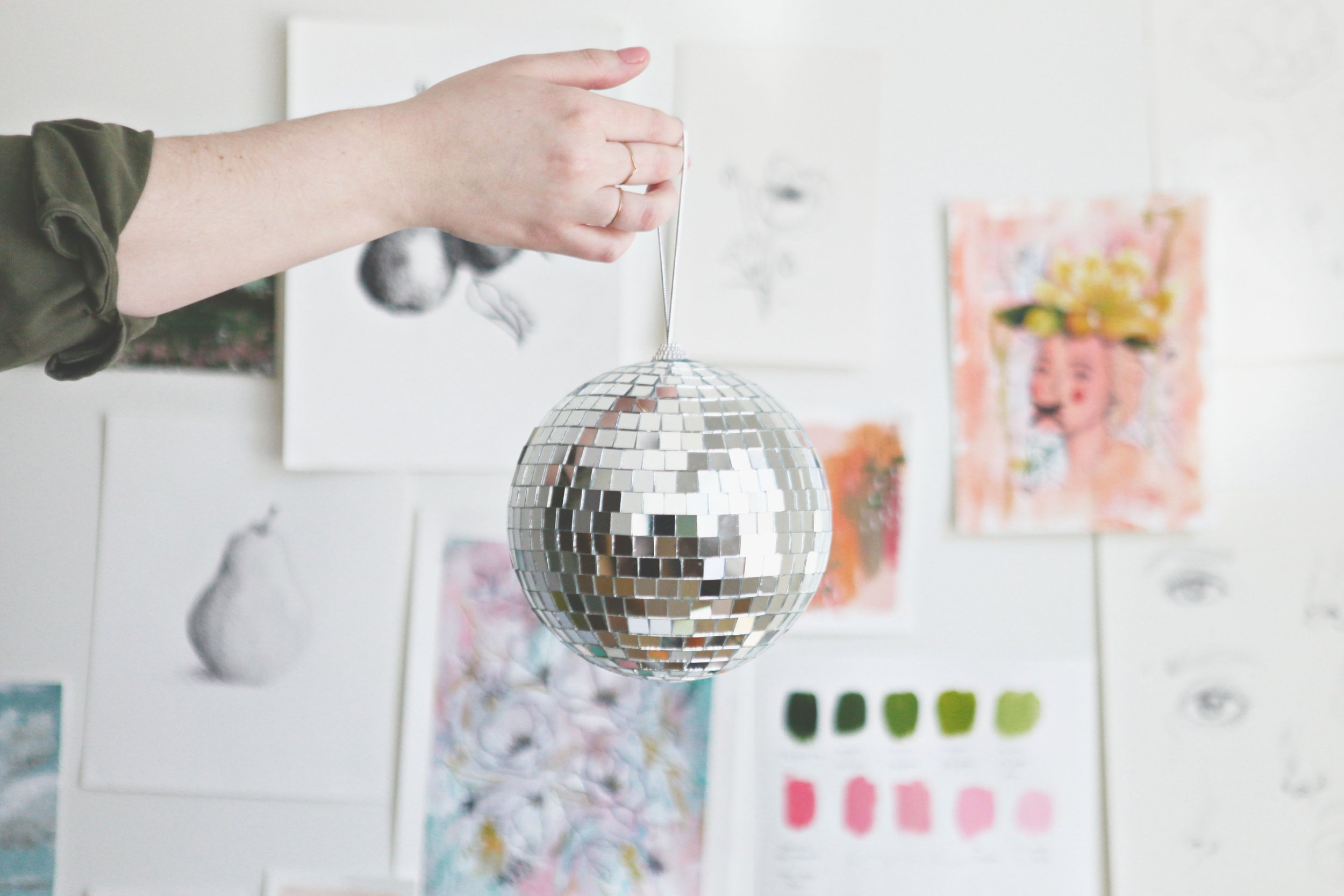 artist Katie Lockhart's hand holding disco ball in art studio space