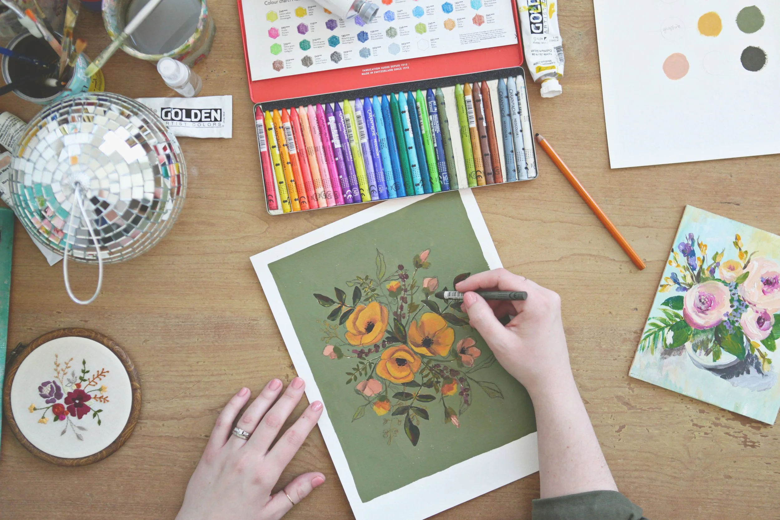 woman artist's hands working at art studo table wiht art supplies
