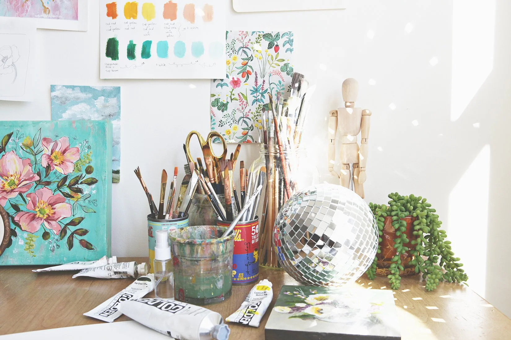 sunlit art studio with paintbrushes, golden paints, and disco ball