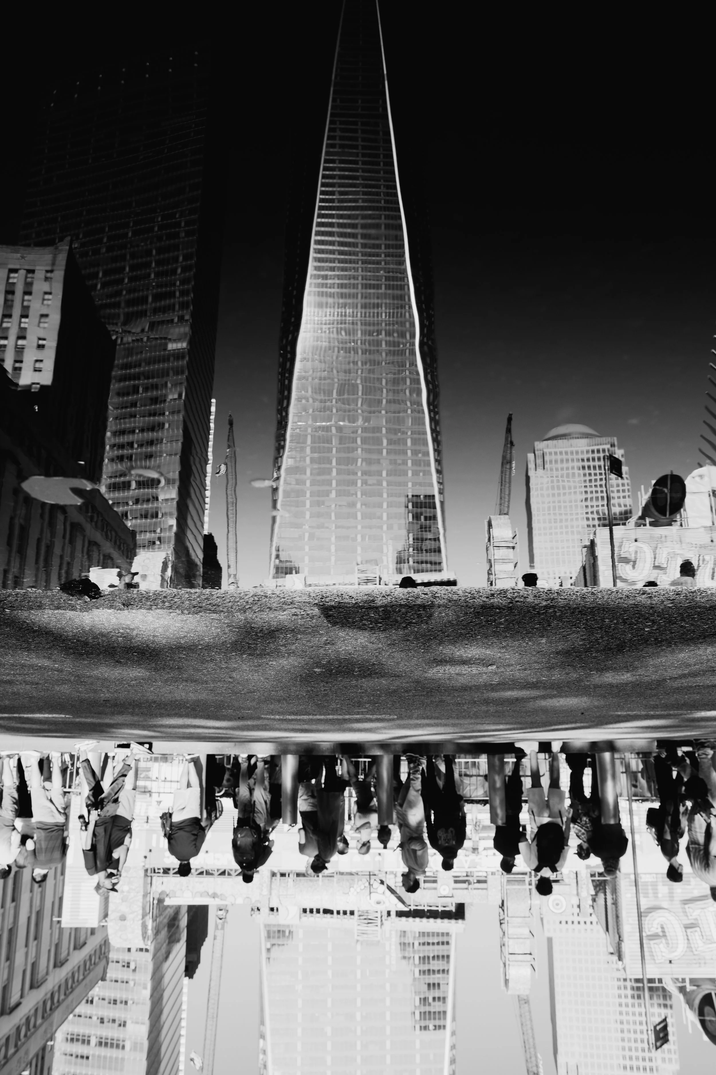 Upside-down black and white cityscape with skyscrapers and people walking along the street.