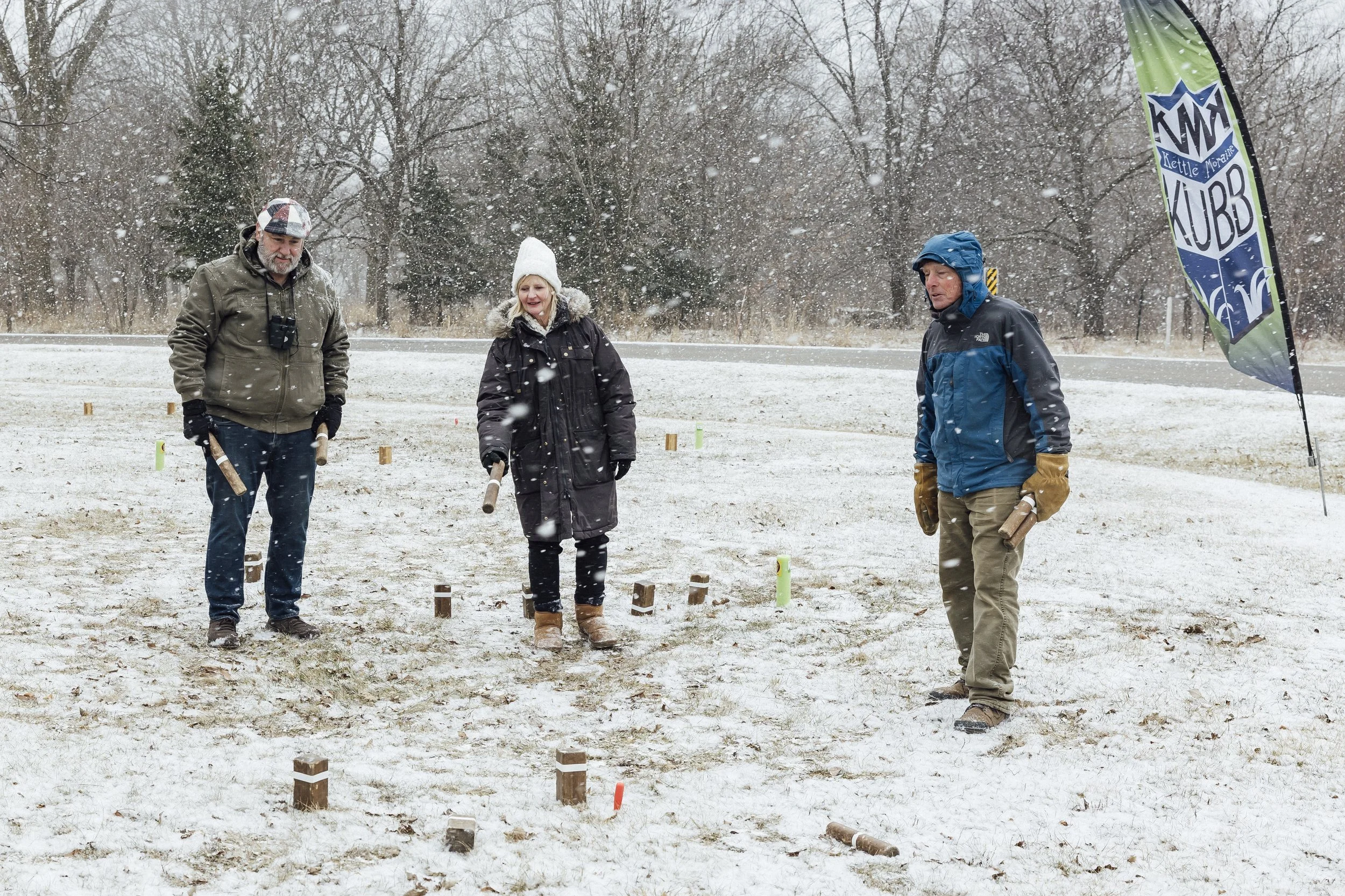 A small group of people playing Kubb, a winter lawn game played by throwing wooden blocks.