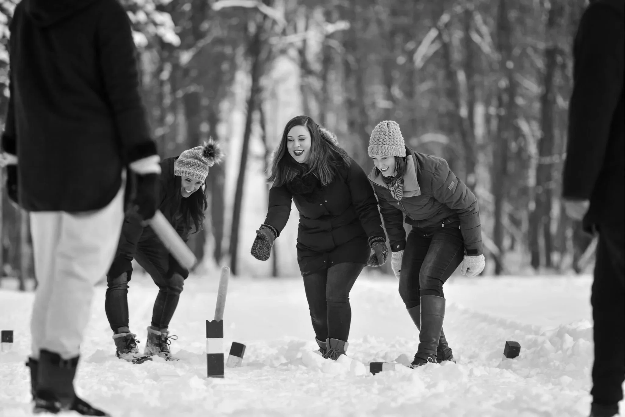 A group of 4 women are outdoor and playing a winter lawn game with wooden batons.