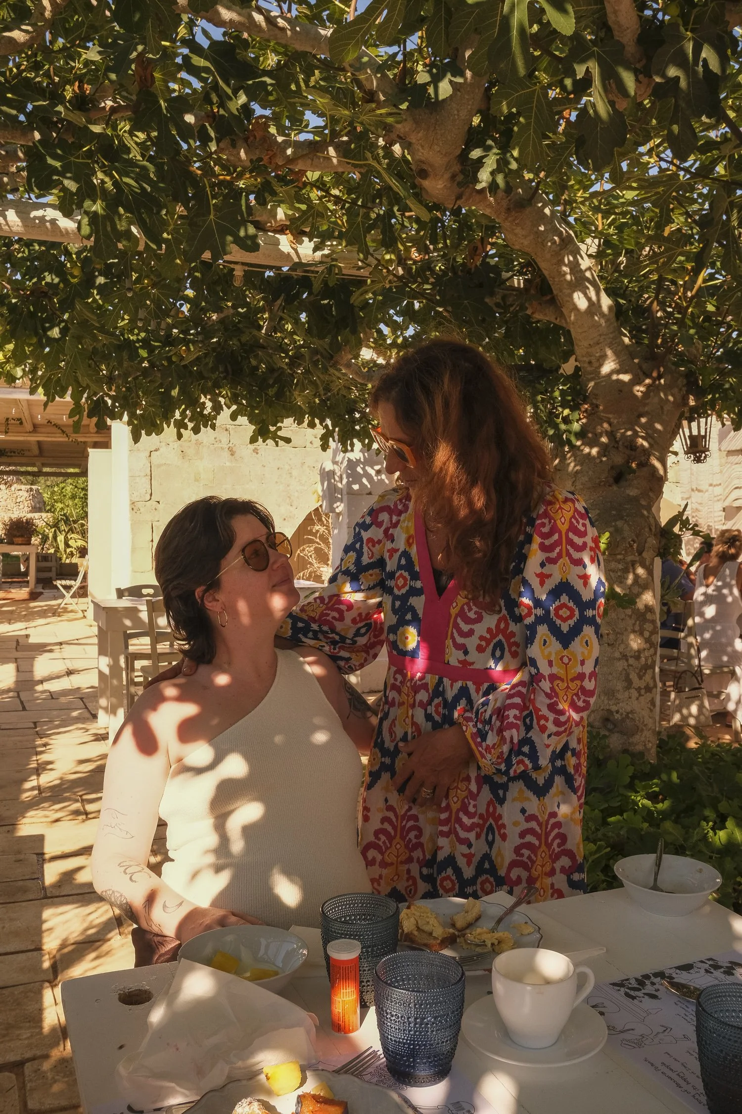 A local Italian masseria host sharing a warm moment with a retreat guest at the breakfast table during a women’s retreat in Italy