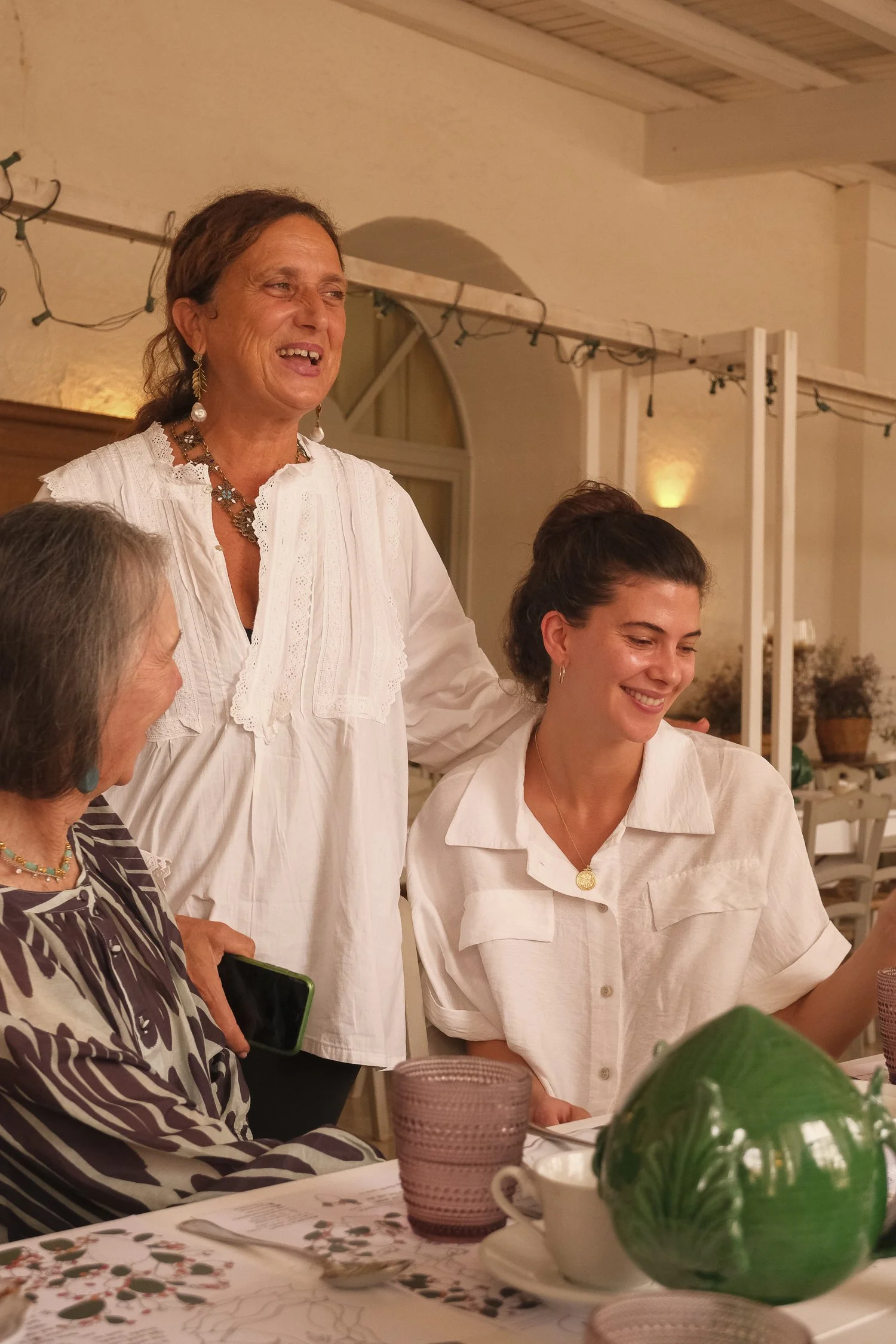 Local Italian host standing behind two retreat guests of different generations, sharing a warm moment at a masseria in Italy.