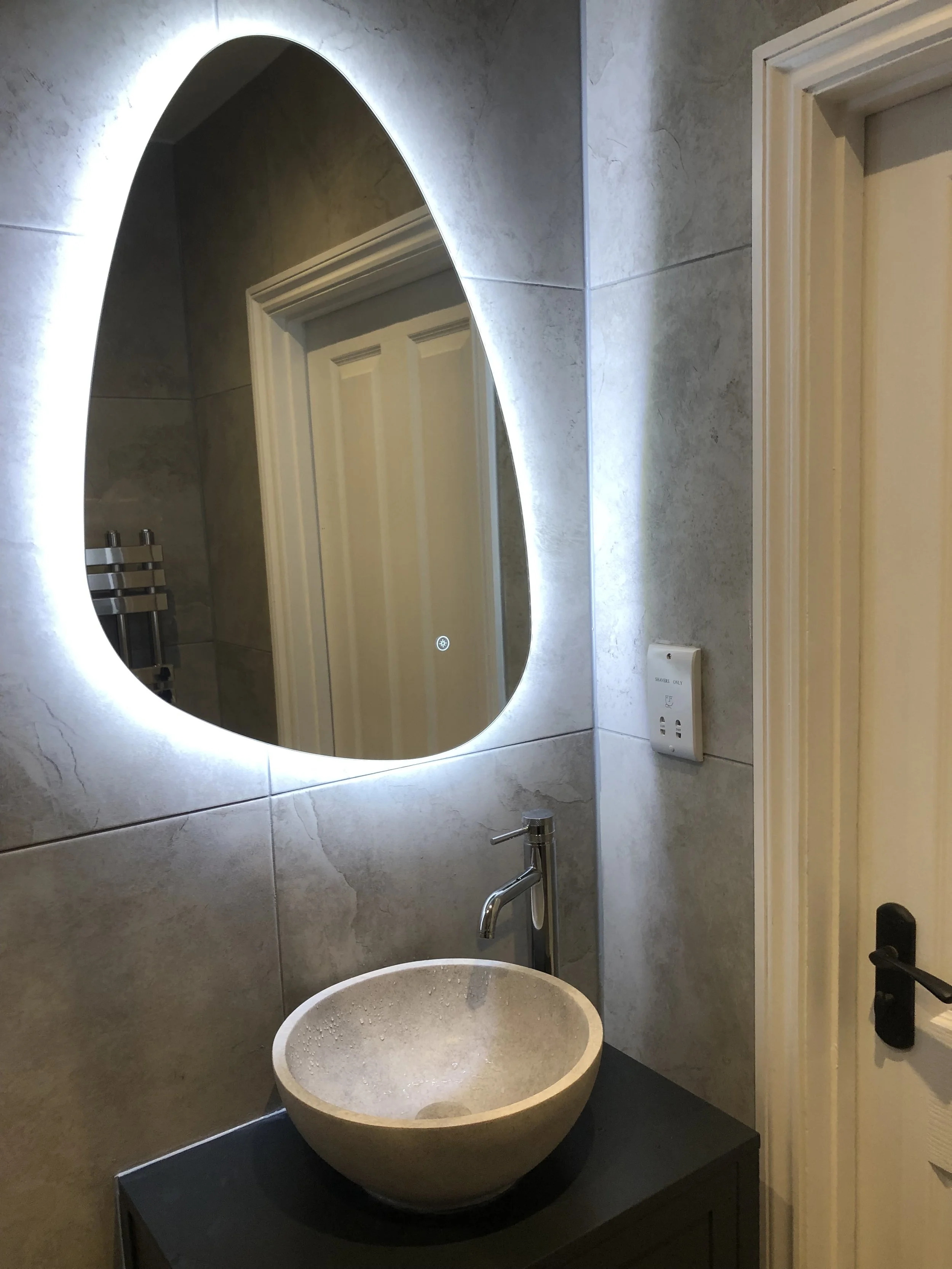 Refurbished bathroom with basin and illuminated mirror