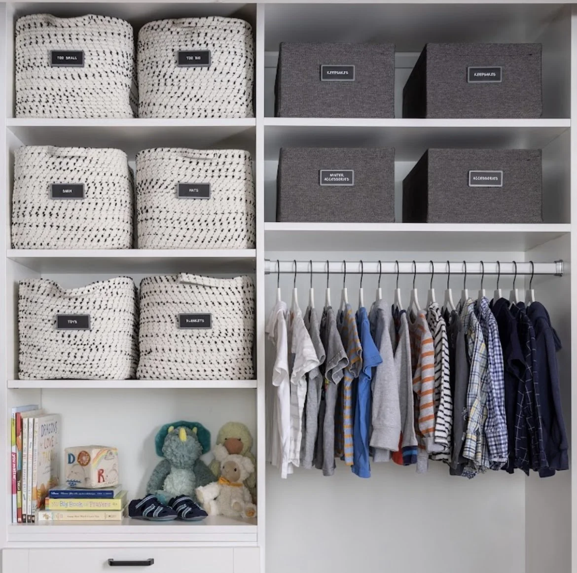 A neatly organized closet shelf with labeled storage bins, hanging clothes, children's toys, and books.