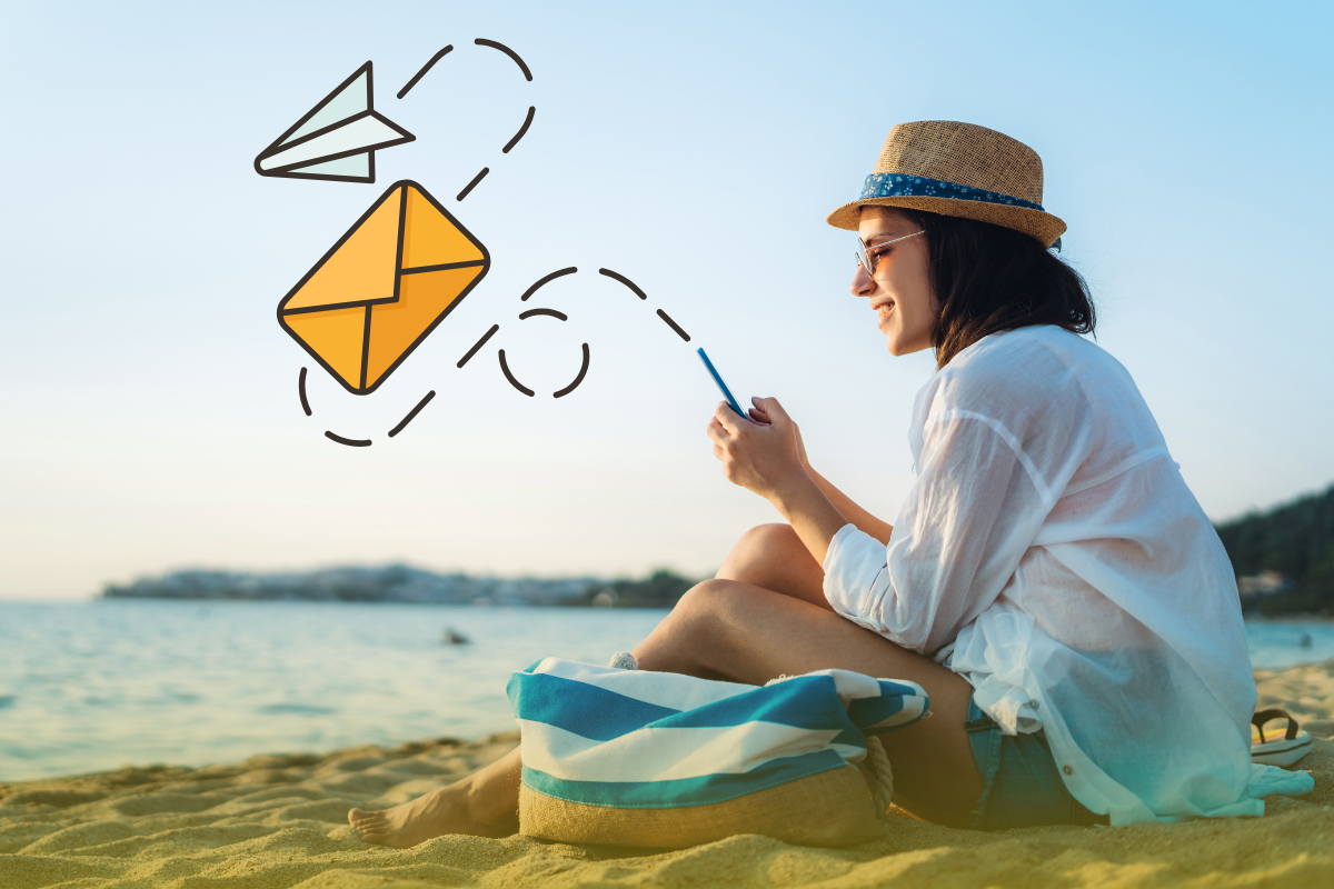 A woman sits on the beach and sends an email from her phone.