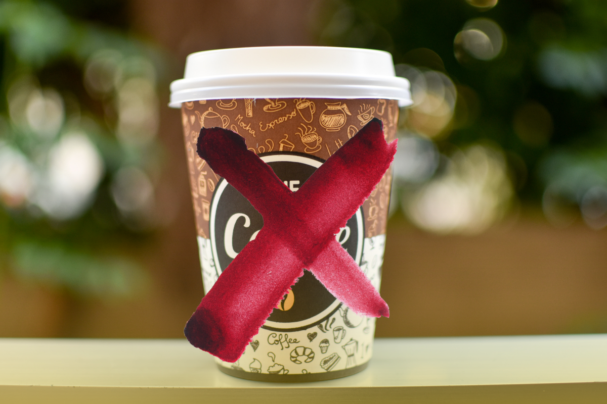 A travel coffee cup with a red X over the logo.