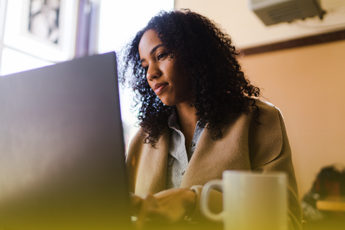 woman sits at a computer writing a bio - EO Report