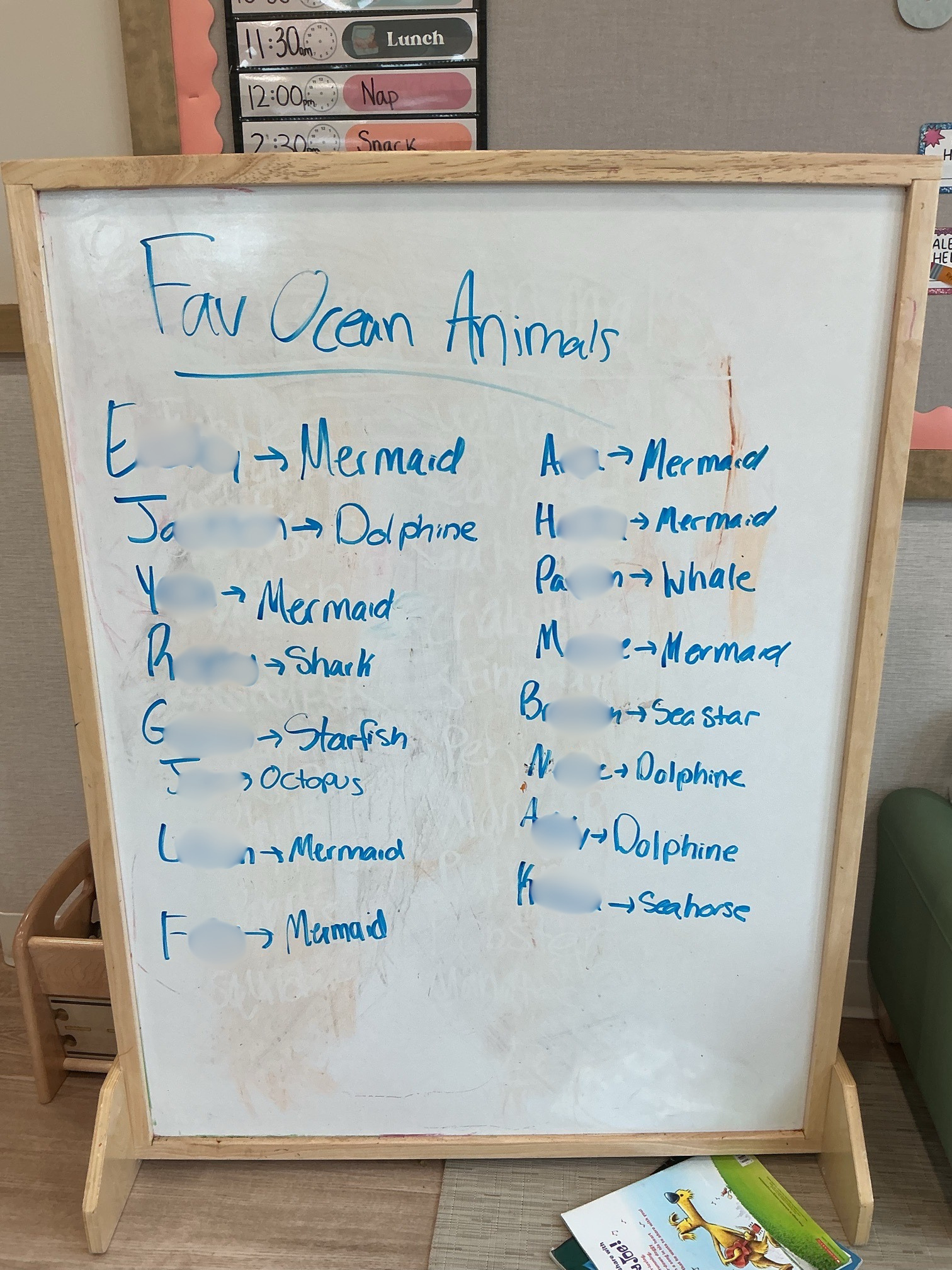 A whiteboard lists the names of children and their favorite ocean animals. The most popular response is "mermaid."