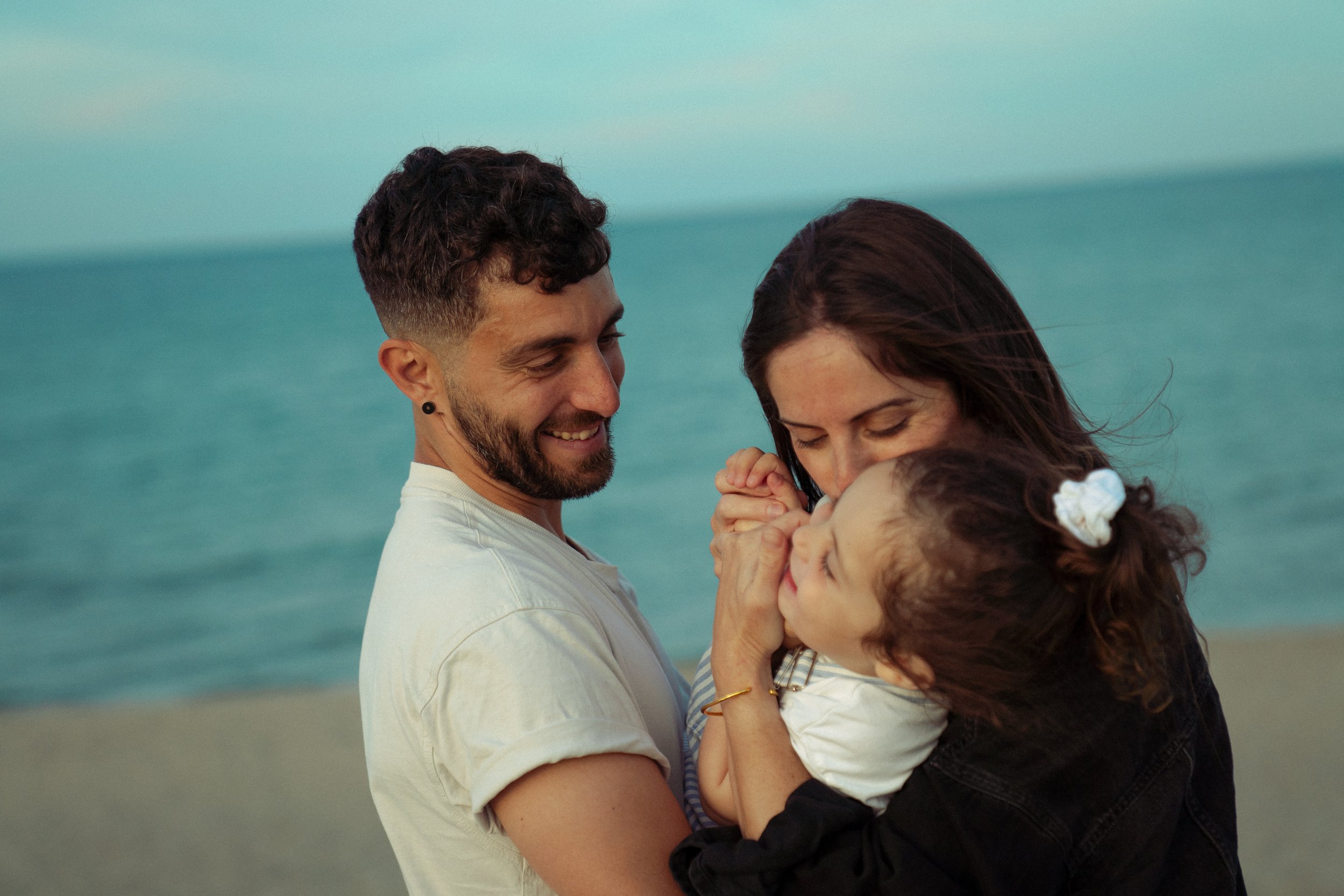 portrait de famille à la plage, le père et la mère portent leur fille dans les bras
