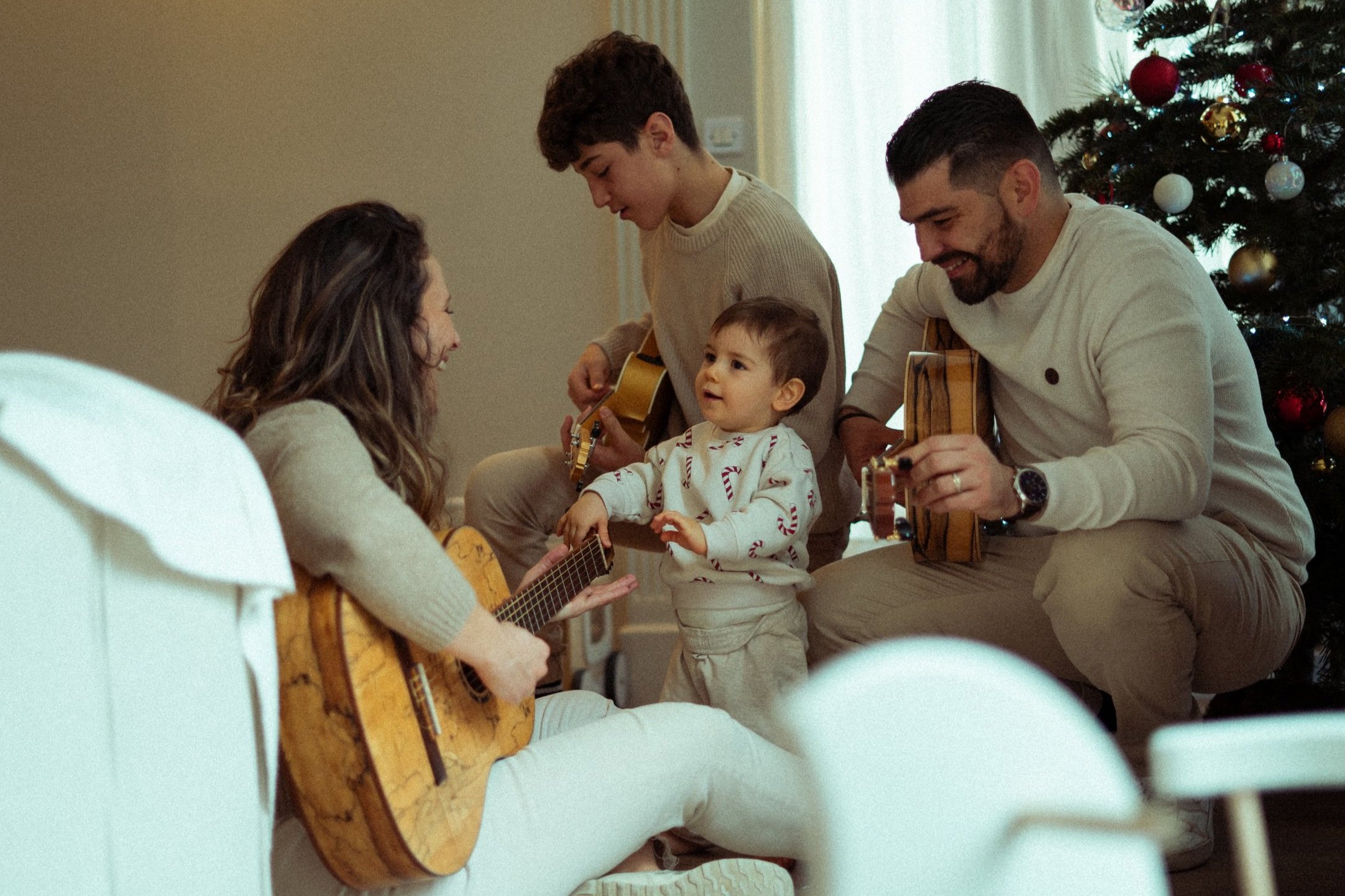 une famille qui joue de la guitare devant le sapin de noel