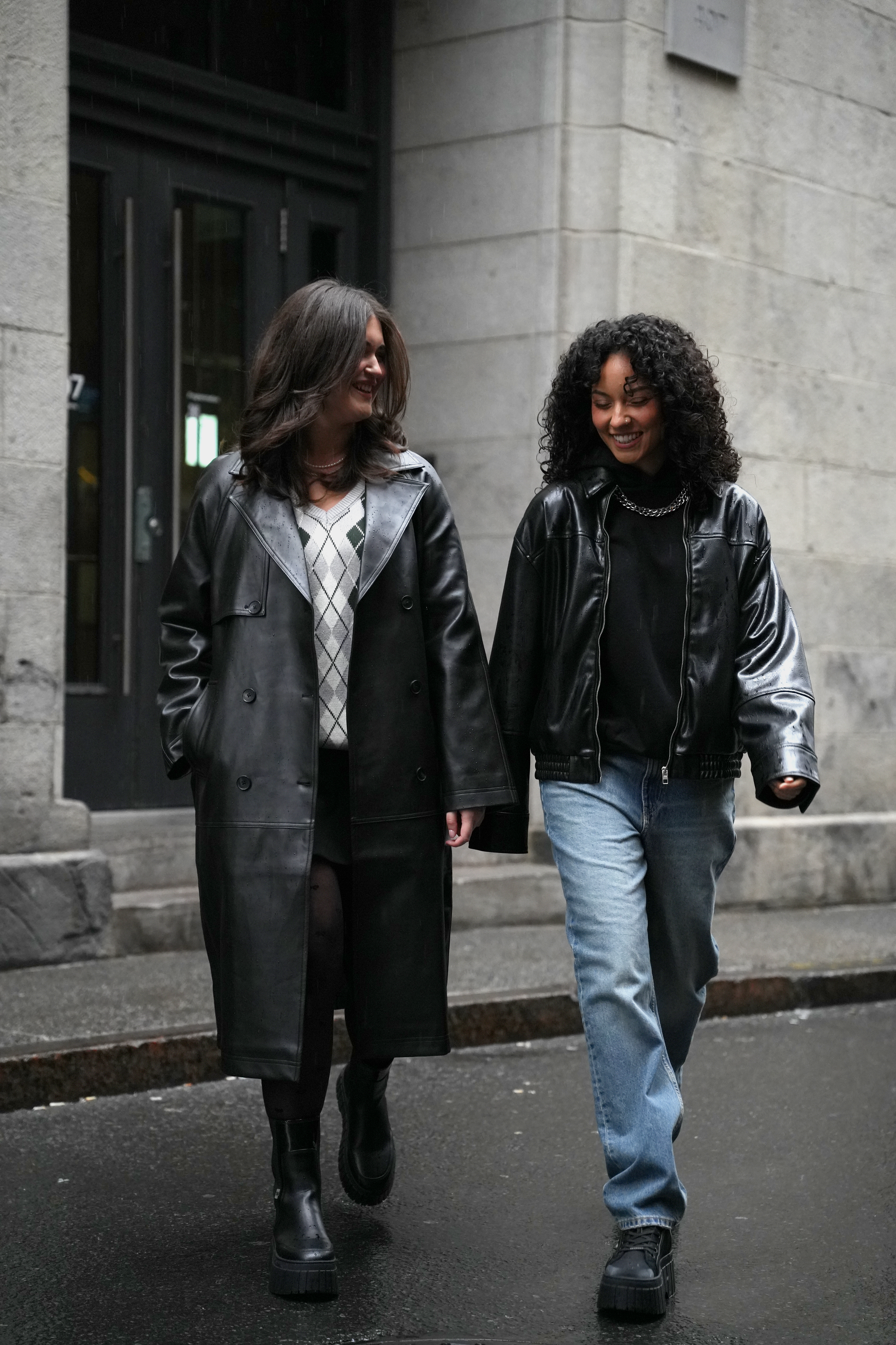 Two women in jackets walking side by side along an urban street.