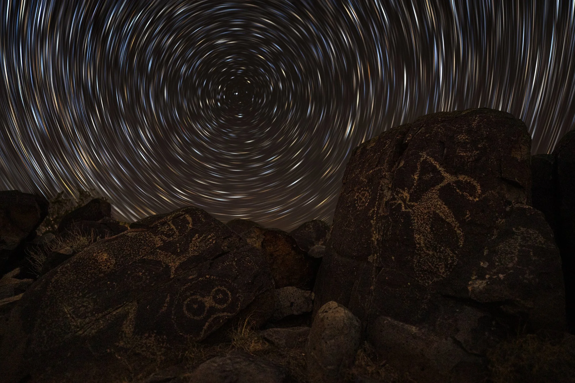 NIGHTSCAPES HONORABLE MENTION: GRAYSON KEMP - "Bedtime Stories." When I saw the final version of this photograph, what struck me were the complementary themes between time, space, and the stories engraved in stone. As the stars traced circles to mark