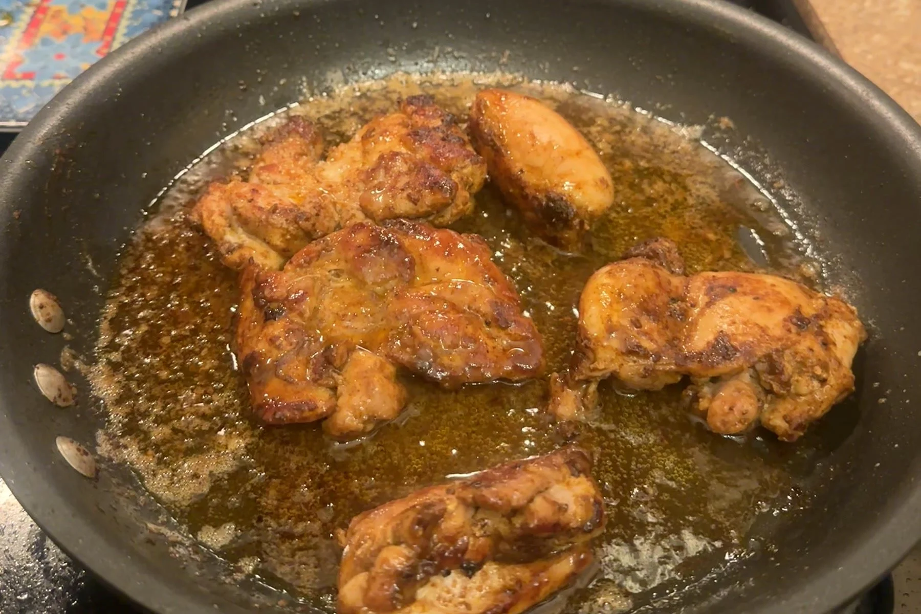 Brown butter chicken thighs glazed in a skillet until golden brown.