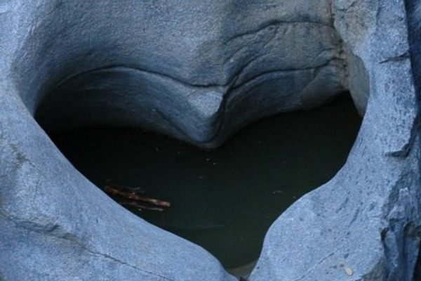 A rock formation with a heart-shaped indentation filled with water.
