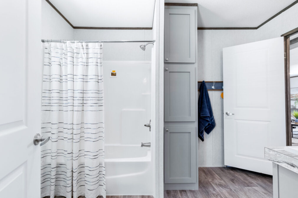Bathroom with shower curtain, gray storage cabinet, and open door leading outside