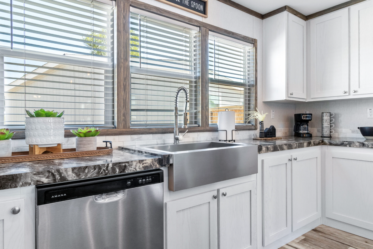 Kitchen with white cabinets, a large window with blinds, stainless steel sink, and black coffee maker. Providing optimal investment opportunity with low barrier to entry and high-yield returns.