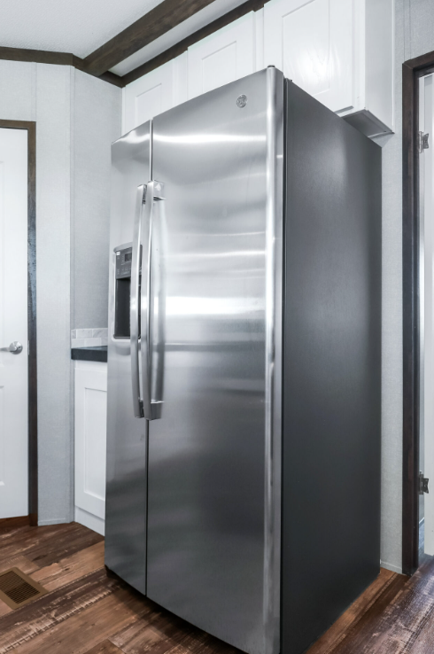 Stainless steel side-by-side refrigerator in a kitchen with white cabinets and wood flooring.