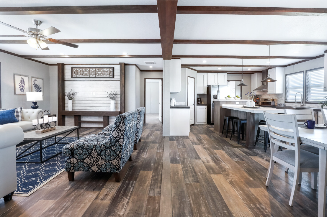 Open concept living room and kitchen with hardwood floors, white walls, and modern furniture.