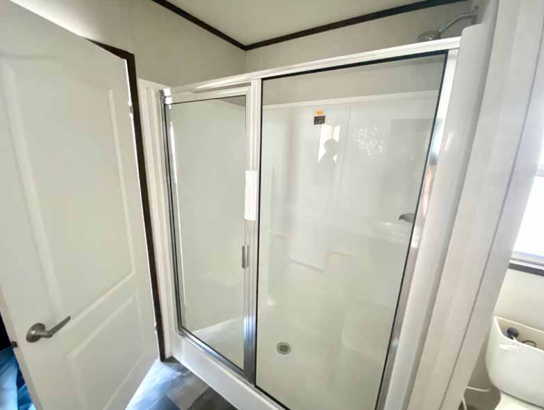 Bathroom with a glass shower enclosure, white walls, a door, and a small window.